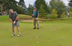 Evert Olkonen and Ken Porter seizes the opportunity for a hole at the newly opened Holmes Harbor Golf Course Thursday morning. The course was packed with all but two of the 22 carts on the greens.