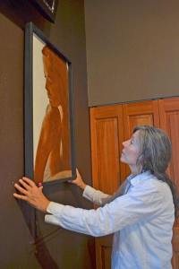 Virginia Bloom adjusts a painting by Ken Hassrick at Blooms Winery Taste for Wine & Art.