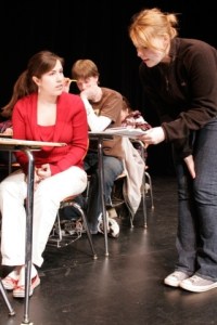 Mindy (Alexis Merculief) is being admonished by Mrs. Mock (Sarah Muncy-Gordon) for disturbing the class during a high stakes test.