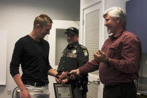 Tony Hartman (right) gives Eric Vasilyev (left) the belt that was used as a makeshift tourniquet to slow blood flow to his injured arm.