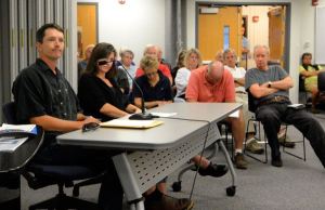 Adam Lind (left) listens during a public hearing in Coupeville Thursday concerning his proposed marijuana production facility in Bayview. A hearing examiner is expected to issue a decision within two weeks regarding whether or not the controversial proposal complies with existing rules and requirements.