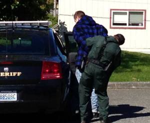 Island County Sheriff's deputy Frank Gomez handcuffs a man outside the Freeland Wells Fargo.