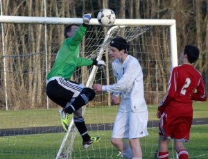 Knight junior keeper Logan Griffis blocks Falcon senior Darby Hayes’ header attempt as Knight freshman defender Bret Matysik closes in during the conference match Friday night.
