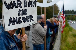 Langley resident Roy Foster holds an anti-war sign at the Saturday Morning Peace Vigil at the Bayview Park and Ride. The group