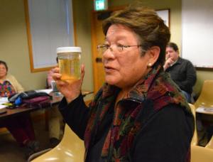 Langley resident Monica Guzman presents a jar of discolored water from her home.