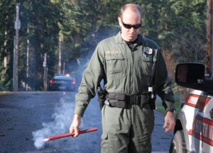 Island County Sheriff's Deputy Dan Todd gets ready to place a flare on Lakeside Drive at Goss Lake after a tree fell onto the roadway