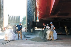 Nichols Brothers employees sweep up the recycled nickel slag the company uses in place of sand. Keeping the yard clean is just one of the company’s efforts to reduce waste and contamination.