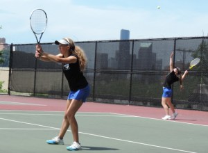 Bayley Gochanour serves during a bi-district girls tennis match in Seattle on May 21. Behind them is the downtown Seattle skyline