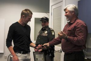Tony Hartman (right) gives Eric Vasilyev (left) the belt that was used as a makeshift tourniquet to slow blood flow to his injured arm.