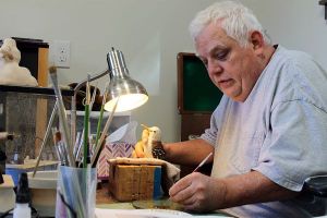 Woodcarver and instructor Don Bundy puts the finishing paint touches on his latest project. Bundy’s work will be featured at Woodpalooza 2016.