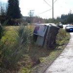 Reserve Deputy Kurt Pepper with the Island County Sheriff&rsquo;s Office speaks with a driver who rolled her Suburban onto its side Thursday on Bayview Road.