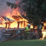 Kyle Jensen / The Record Firefighters lug a firehose around to fight the fire from a different angle.