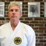 Kyle Jensen / The Record Sensei Warren Berto stands in front of photos of his senseis, who are part of the direct lineage of the Seibukan karate style.