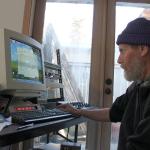 Kyle Jensen / The Record                                George Springer hops on the computer from which he operates Langley Community Radio. The radio station shares the same space as his side businesses, Whidbey Island Moped and RC Quadcopters.