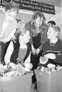 Vivian Rusinko of Gifts from the Heart food bank talks with three Coupeville Elementary School fifth-graders as they organize some of the food donated by students at the school.The students are