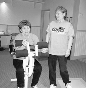 Curves owner Bonnie Davis instructs Carolee Prater on one of the weight machines. Curves is located in about 1