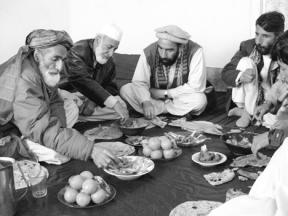 Afghan men in the town of Istalif sit over a meal arranged through a system set up by Impact Teams International. The food distribution system in the war-ravaged town is now handled by village elders.