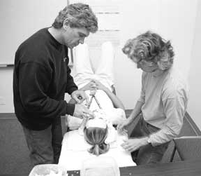 Dave Hanrell and Faith Bushby apply plaster strips to Alexis Stark's face to build a mask she would later paint.