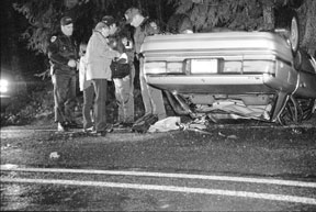 Law enforcement personnel look over a wrecked car Wednesday night shortly after rescue volunteers removed the injured driver and passenger.