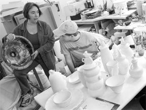 Artist KeKe Cribbs shows Oak Harbor High School cermaic students a glazing concept while senior Patrick Riley gets a closer look.