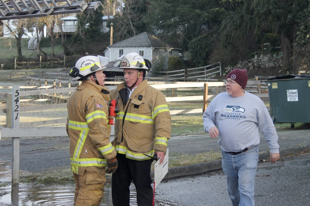 Kyle Jensen / The Record                                Chief Rusty Palmer (left) and Deputy Chief Mike Cotton (right) discuss operations while property owner Andy Campbell comes over to talk to them.