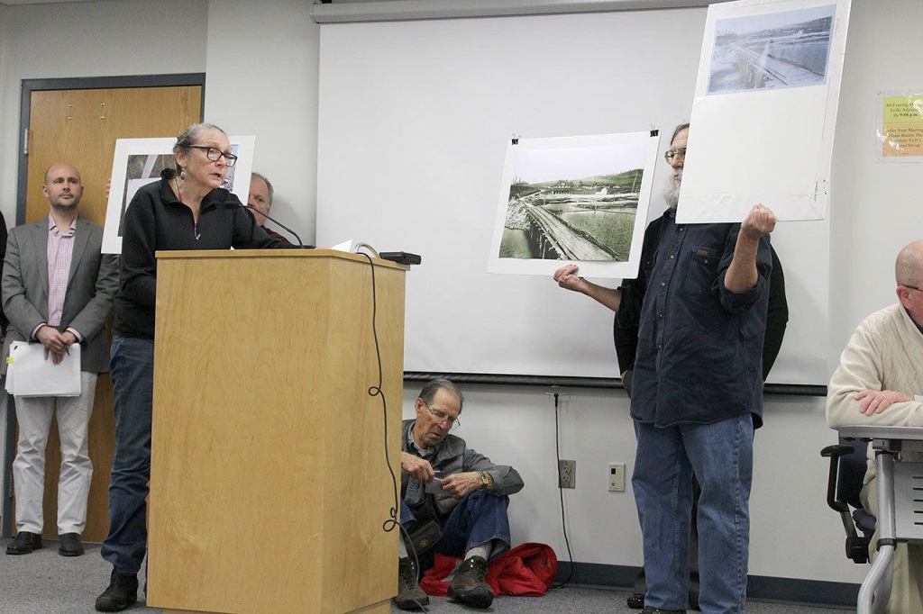 Patricia Guthrie / Whidbey News Group                                Steve Erickson holds up signs showing the disputed Wonn Road beach as Jane Seymour, attorney for the group Island Beach Access, urges Island County commissioners to reject a settlement that ultimately was approved in a 2-1 vote.