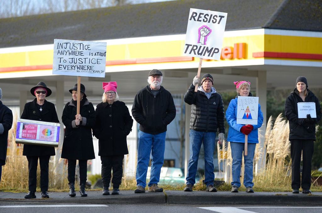 Justin Burnett / The Record &mdash;                                 Protesters waves signs opposing President Donald Trump on the corner of Fish Road and Highway 525 in Freeland on Friday. More than 60 people attended the event.