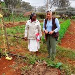 Contributed photo &mdash; Anza Meunchow (right) is taken on a tour of a convent&rsquo;s community garden in Nairobi. The nets that cover the garden is used to keep out monkeys, which are one of the primary pests to Kenyan farmers.