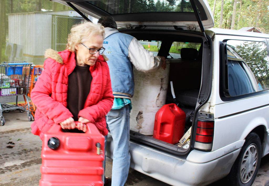 Freeland residents, Bob Brower and Debra Whitson, get help disposing of 90 gallons of gasoline that had been sitting on a boat for eight years. Photo by Patricia Guthrie/Whidbey News-Times