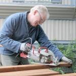 Evan Thompson / The Record &mdash; Rusty Palmer, a volunteer with Hearts & Hammers and fire chief at South Whidbey Fire/EMS, saws wood that was used to build a 70-foot fence for a homeowner.