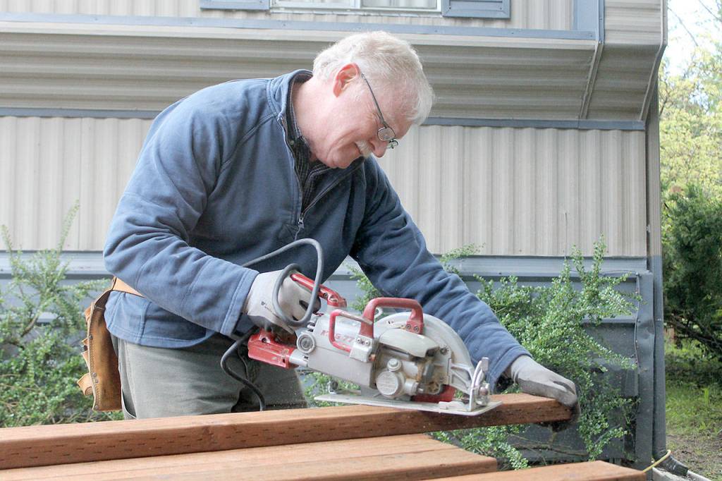 Evan Thompson / The Record &mdash; Rusty Palmer, a volunteer with Hearts & Hammers and fire chief at South Whidbey Fire/EMS, saws wood that was used to build a 70-foot fence for a homeowner.
