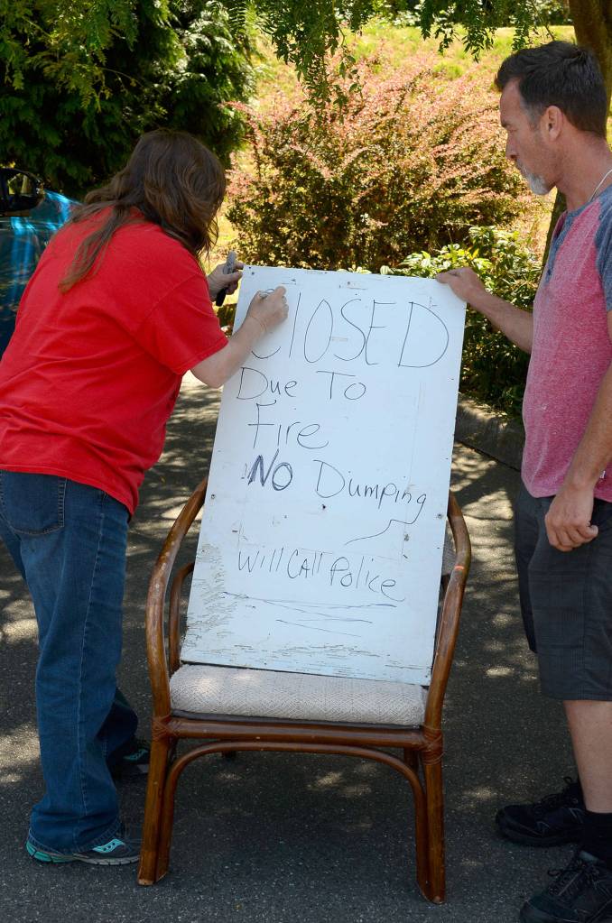 Justin Burnett/The Record &mdash; Lavena DeClercq and Stephen Lyons, employees at Senior Thrift in Freeland, make a sign alerting patrons to a Sunday fire that has closed the business until further notice.