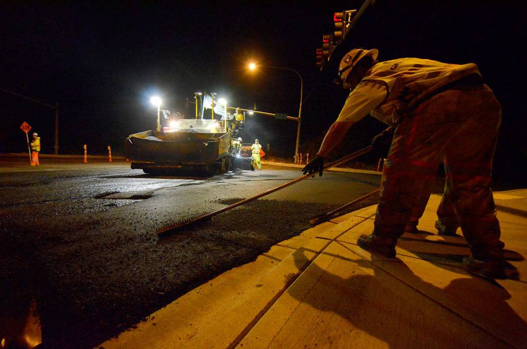 Justin Burnett/The Record &mdash; Granite Construction workers Jessie Littlefox Long and Bill McGuire smooth out freshly laid asphalt at the intersection of Highway 525 and Fish Road in Freeland on Thursday.
