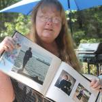 Evan Thompson / The Record &mdash; Kat Ersch holds up a photobook that includes pictures of her late husband, Bill Davison, a 22-year Navy veteran.