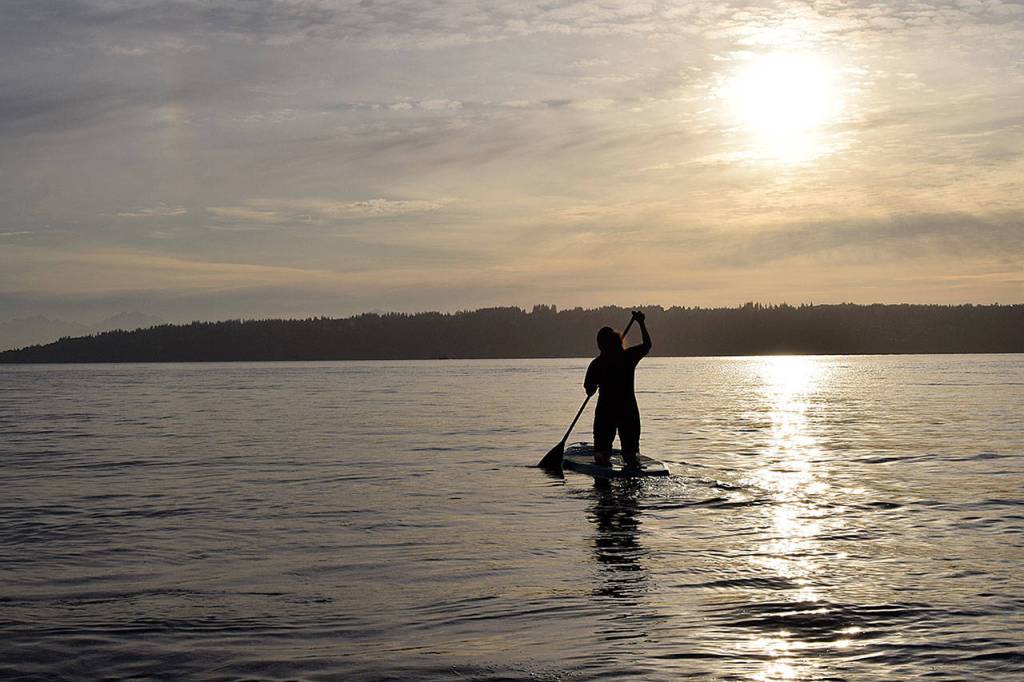 Kyle Jensen / The Record &mdash; Aja Stewart paddles out into Puget Sound to practice yoga and meditate.
