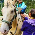 Aida Daly saddles up on Tango with instructions from Sue Landusky, owner of Stride &lsquo;N Glide. Daly was treated to a birthday trail ride with her family by her grandmother. Photo by Patricia Guthrie/Whidbey News-Times