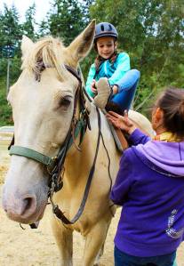 Aida Daly saddles up on Tango with instructions from Sue Landusky, owner of Stride &lsquo;N Glide. Daly was treated to a birthday trail ride with her family by her grandmother. Photo by Patricia Guthrie/Whidbey News-Times