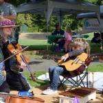 Kyle Jensen / The Record &mdash; More than 30 booths were stationed at Children&rsquo;s Day, including one manned by Island Strings. Instructors like Talia Marcus, left, gave kids quick music lessons.