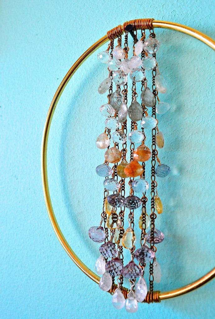 Alexa Allamano photo &mdash; Allamano makes home decor in addition to jewelry. In this piece, 52 gemstones are tethered to vertical chains and suspended in the center of a brass oval.