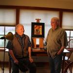 Twin brothers Dan and Mike Burroughs are both artists but with different styles. Mike (left) does ink and watercolor sketches and Dan paints with oils. Between them is one of Dans paintings. Photo by Patricia Guthrie/Whidbey News-Times