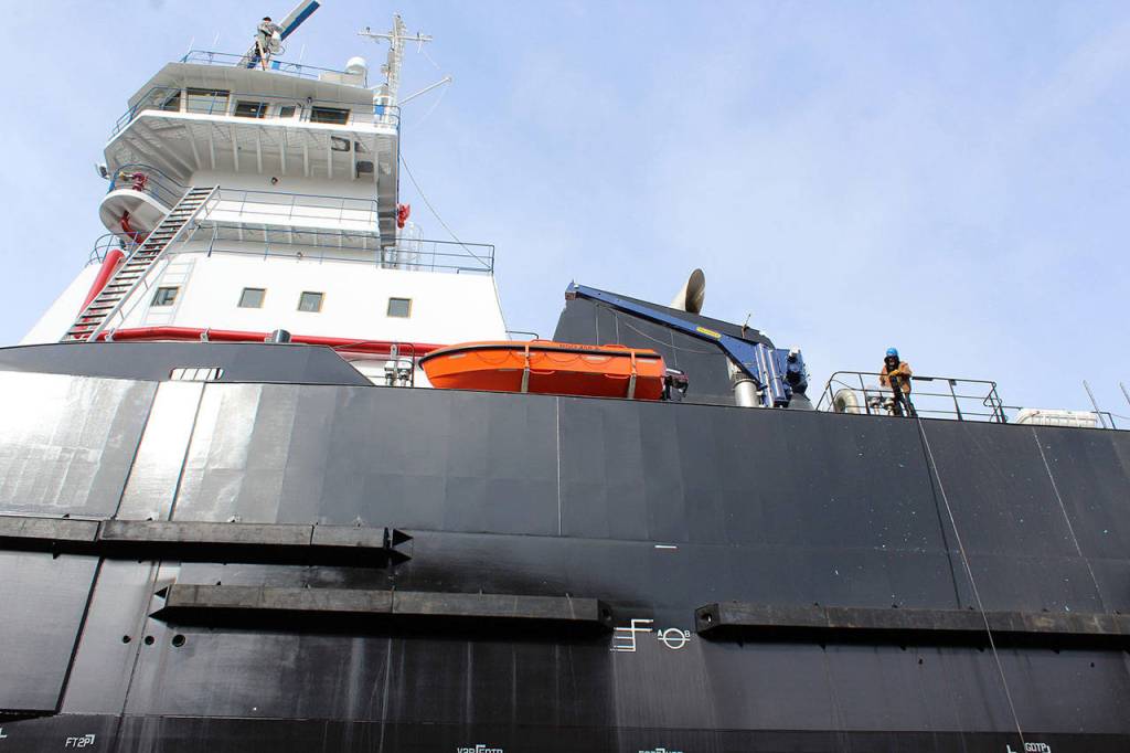 Workers look like as tiny as bait atop the tug boat that took about one year to construct. Its built to attach to a barge.