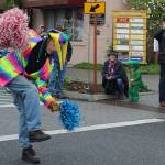 A crocodile sitting on the curb and others along the parade route watch Conducter of Fun Jim Freeman do his thing.