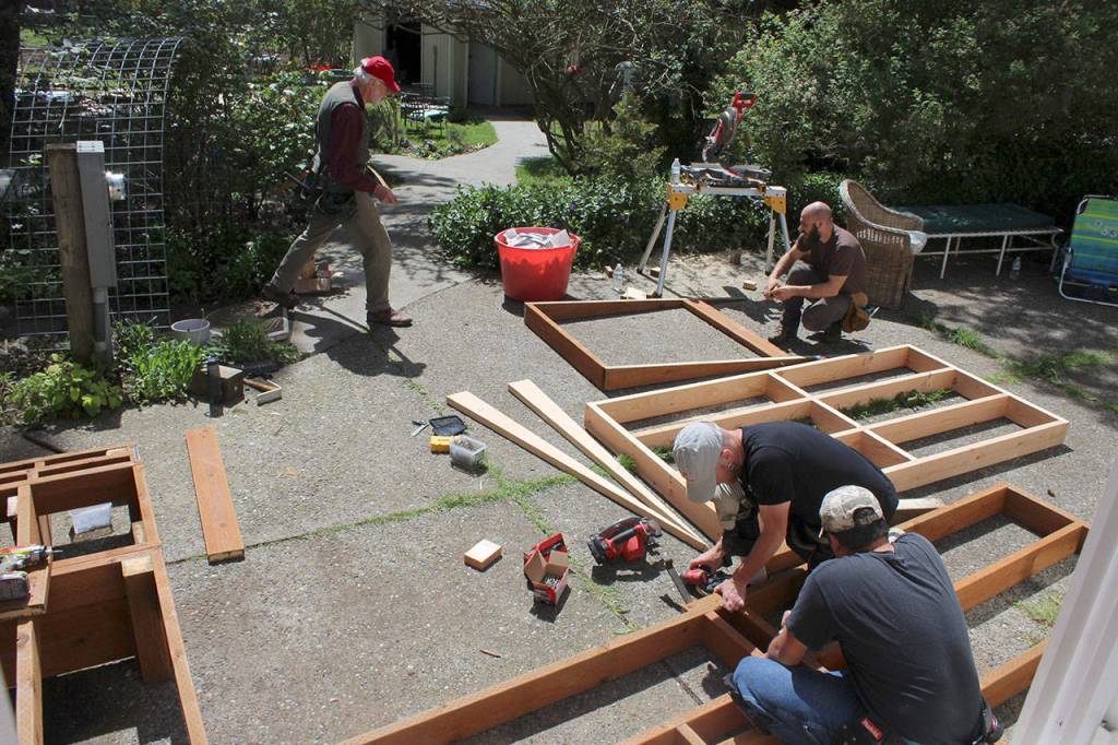 A volunteer team puzzles out how to fit an outdoor ramp onto a small patio area Saturday in Freeland. A mother of an adult disabled daughter wanted to be sure she created a functional space for her child to live with a caretaker in the future.