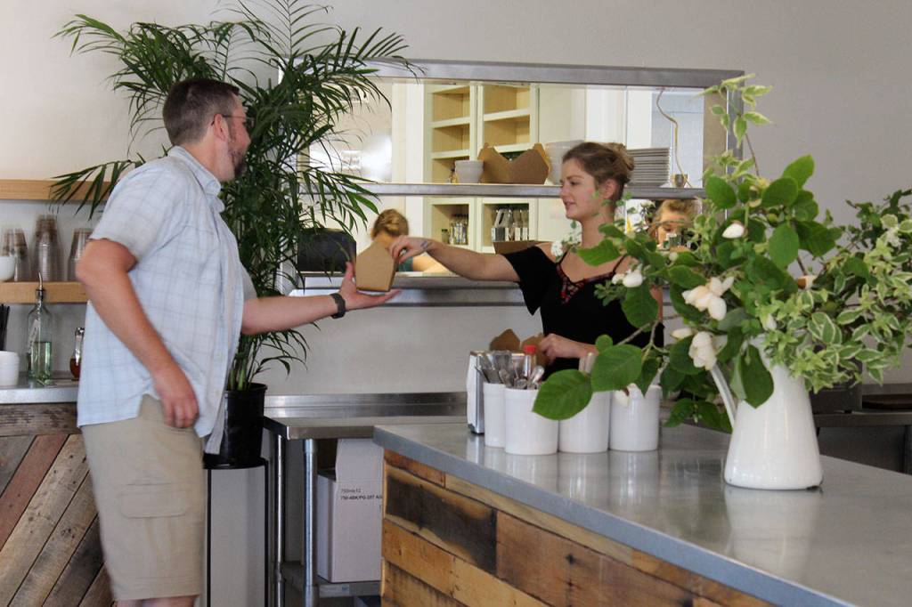 Lexi Parrick helps a customer in front of the cafes new kitchen pick-up window. The restaurant added 1,200 square feet, including a full kitchen with a grill, oven and plenty of space to prep.