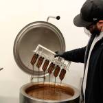 Whidbey Island Ice Cream employee Joe Valencia dips triple berry bars into dark chocolate before putting them into the freezer. Photo by Patricia Guthrie/Whidbey News Group