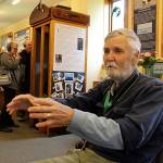 Howard Garrett of Orca Network talks about the new underwater listening booth at the Langley Whale Center while a couple listens through headphones in the background. The exhibits uses a renovated maple telephone booth. Photo by Patricia Guthrie/Whidbey News Group