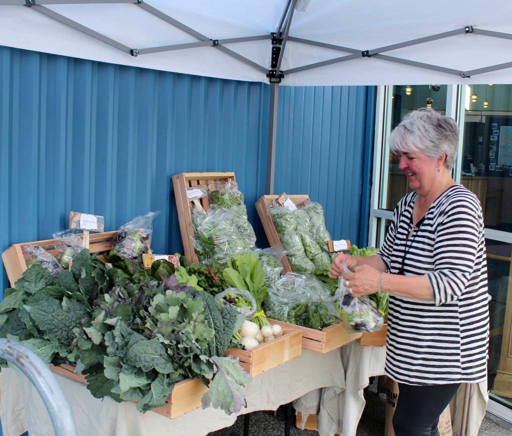 Judy Feldman sets up veggies for sale in front of the Island Athletic Center. Theyre grown at the Organic Farm School which has eight students this season.