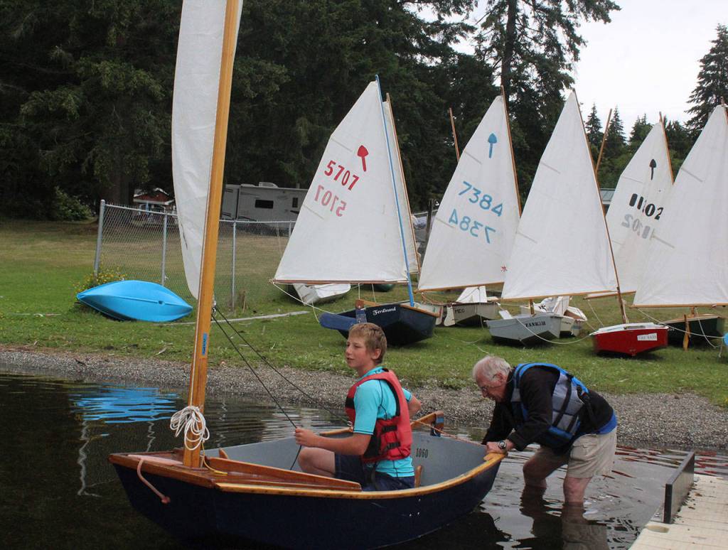 During a youth sailing program, Colin Byler gets a push off Deer Lake beach by instructor Bill Brown.