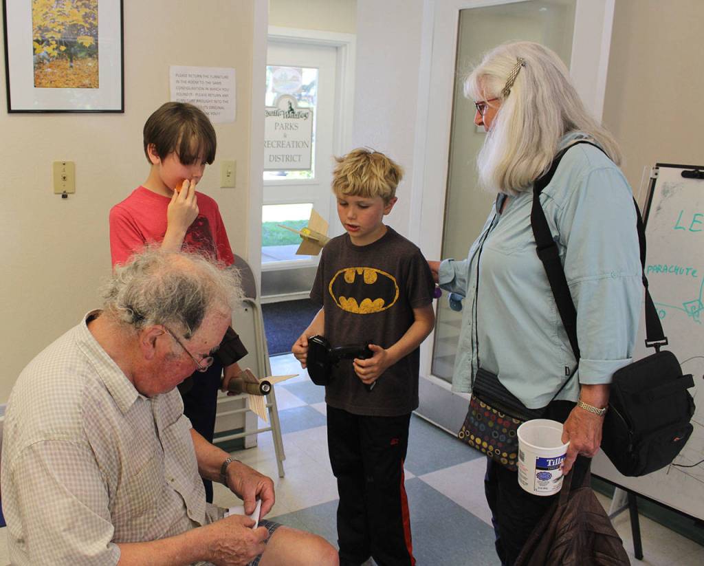 At the end of the three-day Model Rocket Mini Camp, Leonard Good attends to a last-minute repair request of Caleb Arndt (wearing Batman shirt) as his brother, Griffin, and grandmother, Bonnie Arndt, look on. The boys father took the same class from Good 35 years ago.