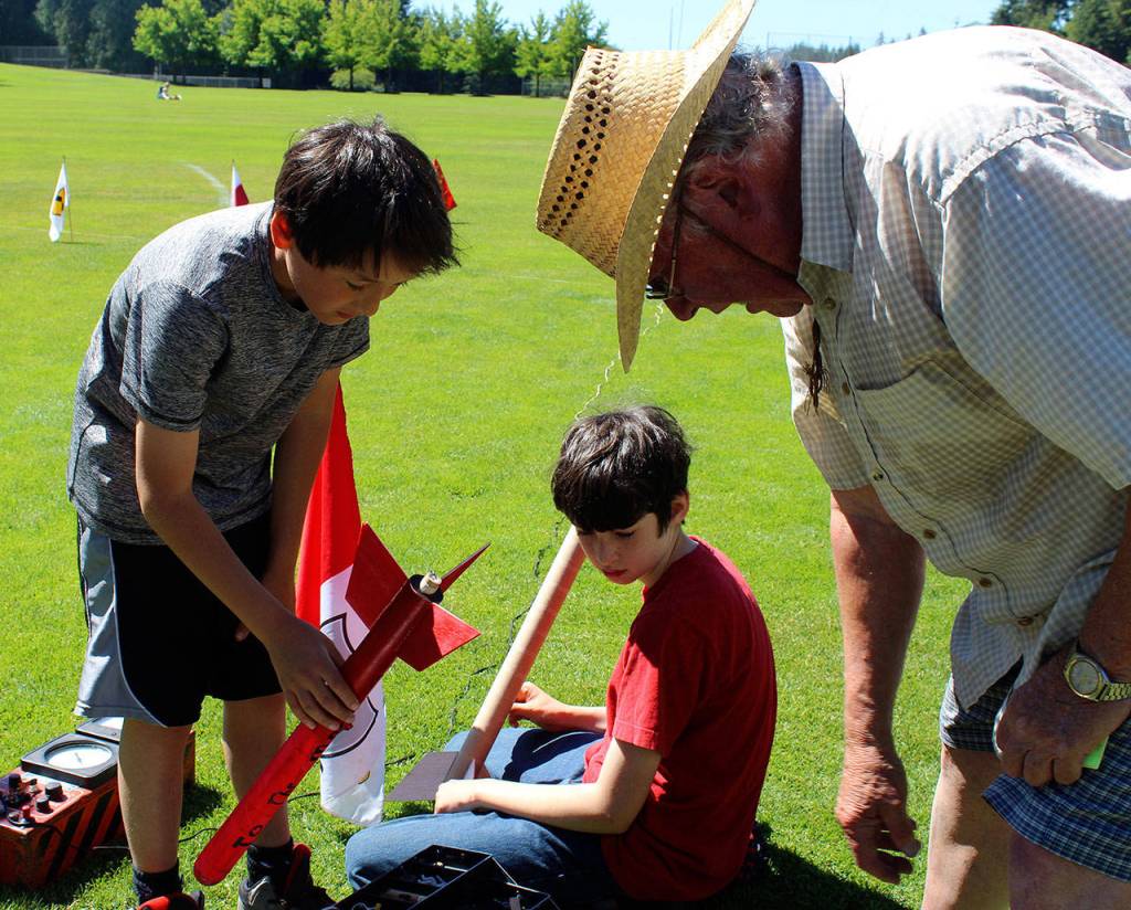 Leonard Good helps Jamie Dale (left) and Liam OBrien (center) prepare their spacecraft for flight.